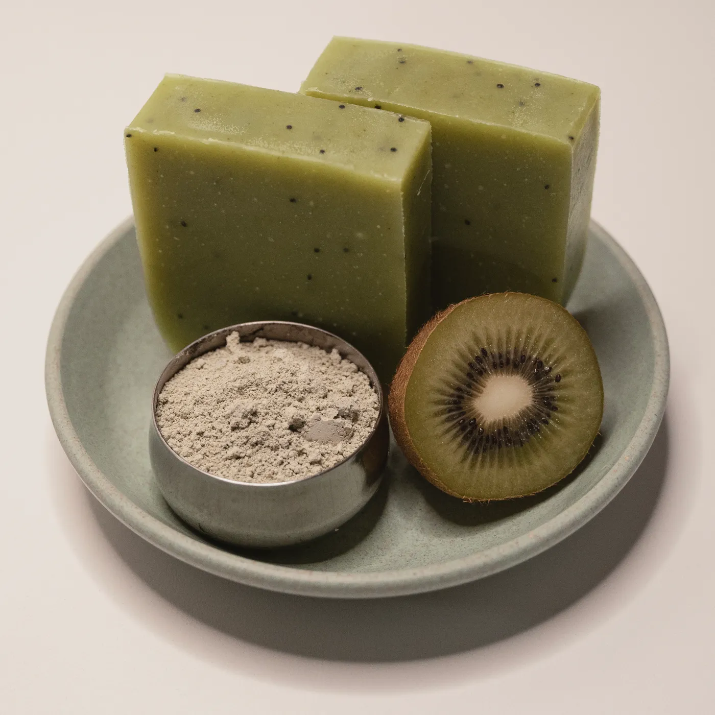 Kiwi soap on a green dish beside a scoop of pale clay